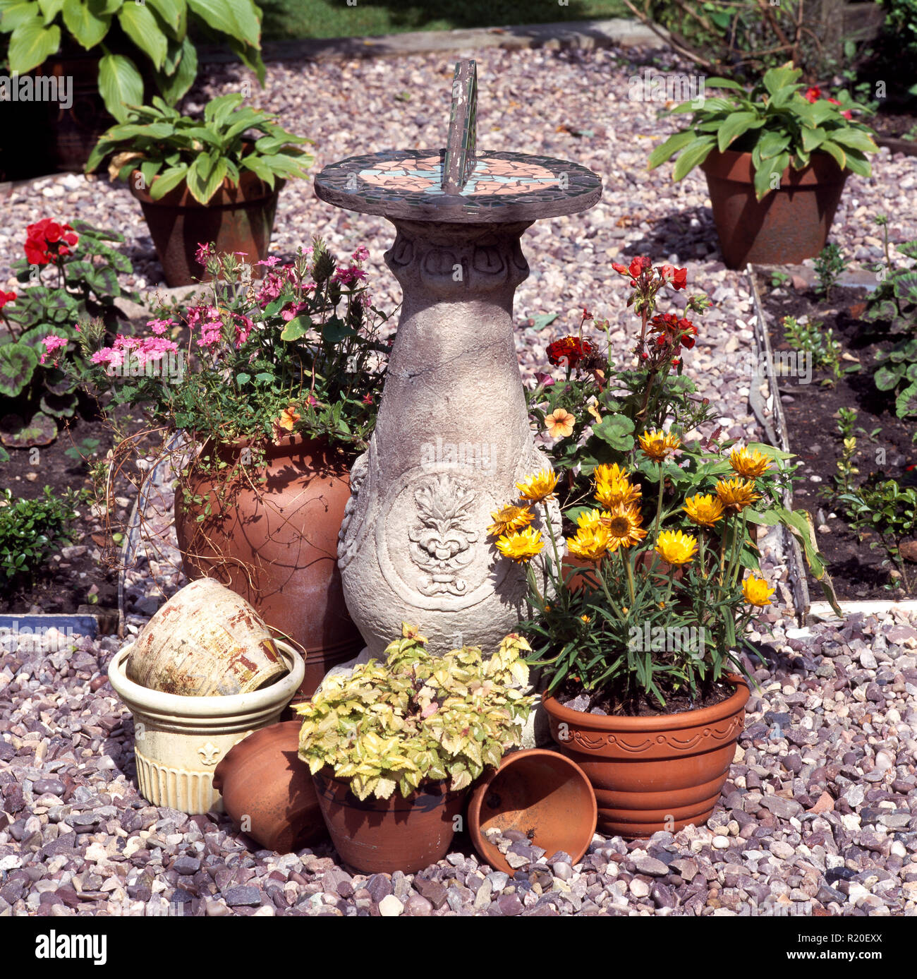 Sundial and pots of annuals on gravel Stock Photo