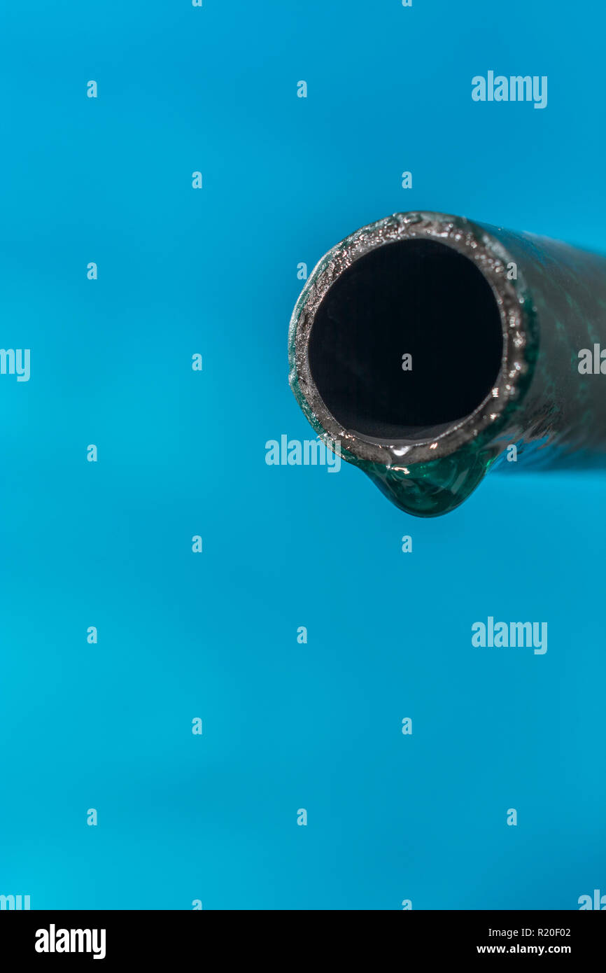 Plastic garden hosepipe / PVC hose pipe with last water drop against blue background. For leaks, 2018 UK heatwave, UK drought, and European droughts. Stock Photo