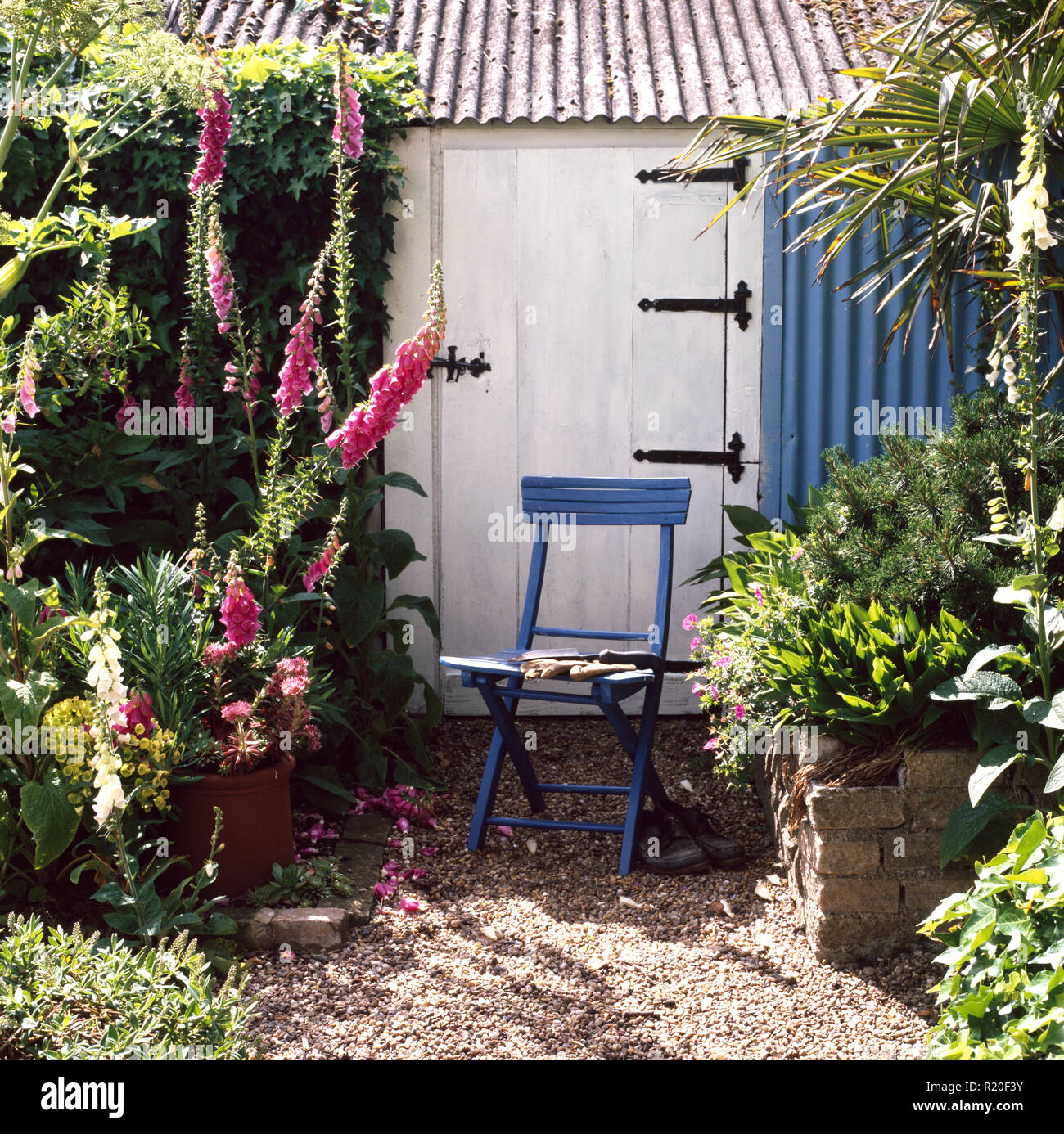 Blue chair in front of garden shed sith corrugated panel and roof Stock Photo