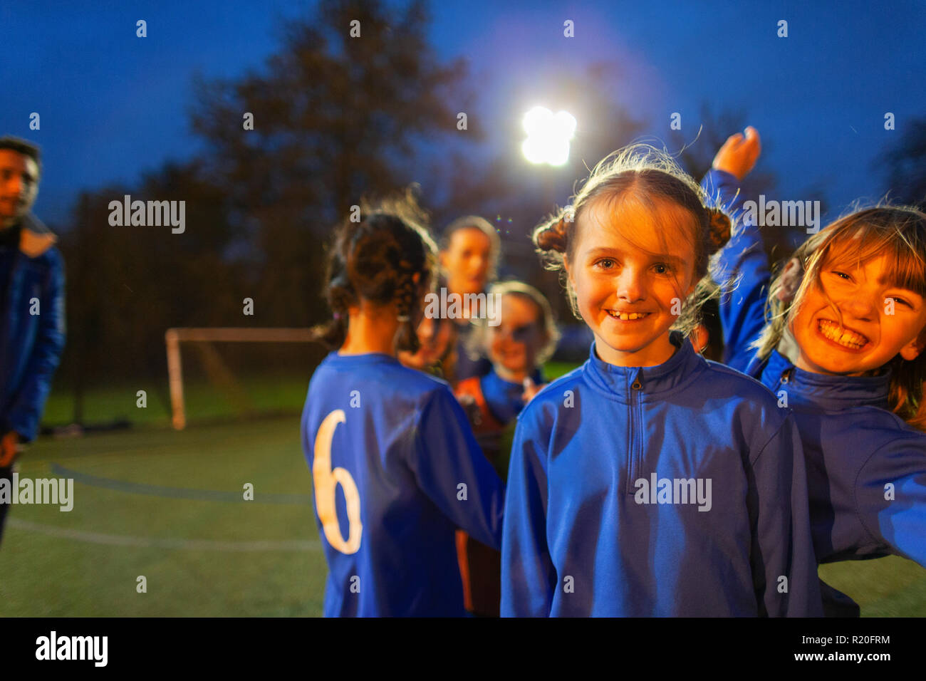 Portrait confident, happy girl soccer players on field at night Stock Photo