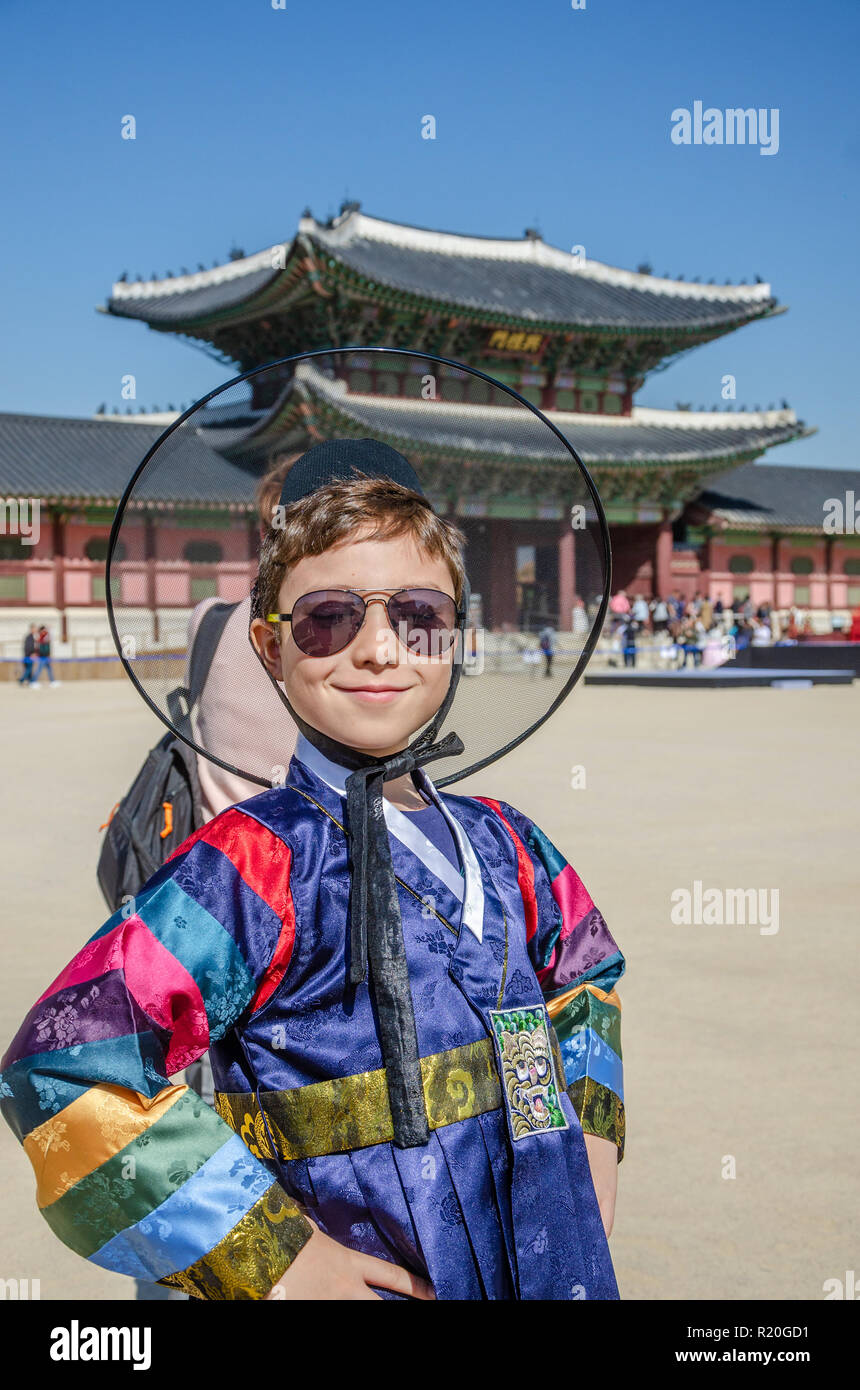 A boy smiles and poses for a portrait wearing traditional Korean dress in front of  a gate into Gyeongbokgung Palace in Seoul, South Korea. Stock Photo