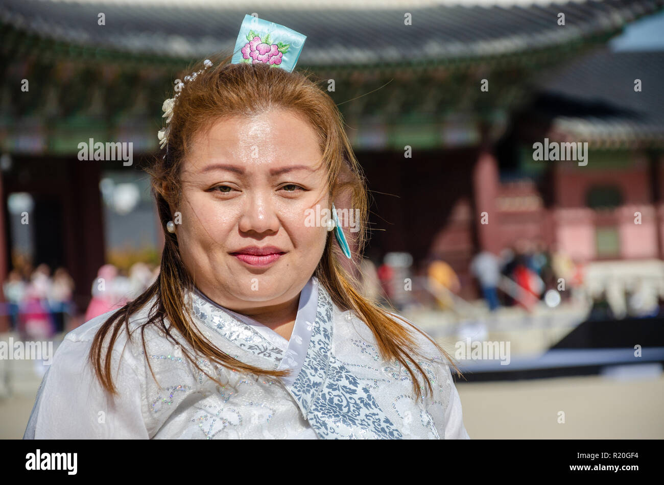 Lady tourist dressed up in traditional Korean dress, a hanbok, stood posing and smiling. Stock Photo