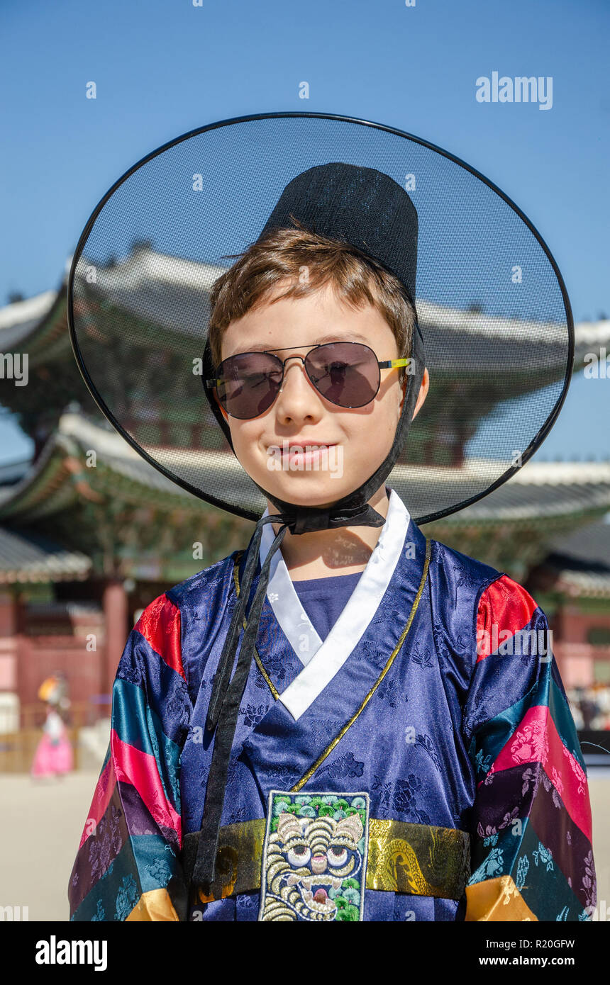 A boy smiles and poses for a portrait wearing traditional Korean dress in front of  a gate into Gyeongbokgung Palace in Seoul, South Korea. Stock Photo