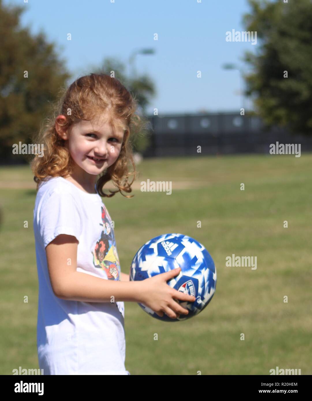 6 year old redheaded girl holding soccer ball Stock Photo