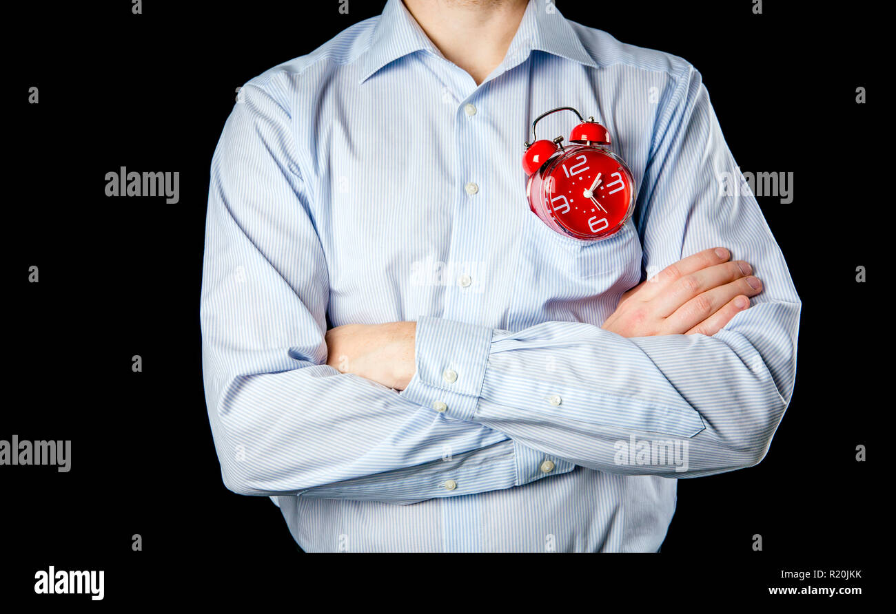 Adult male wearing formal shirt and hands crossed holding big red vintage alarm clock. Time concept. Stock Photo