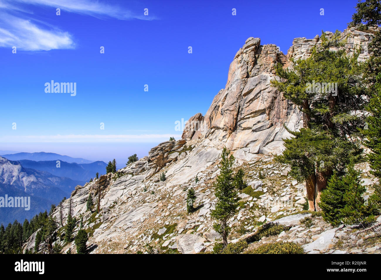 High altitude landscape in Sequoia National Park, Sierra Nevada mountains; blue sky and smoke from wildfires covering the valley visible in the backgr Stock Photo