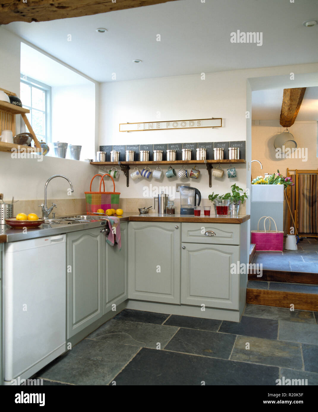 Slate flooring in kitchen with pale grey fitted cupboards Stock Photo