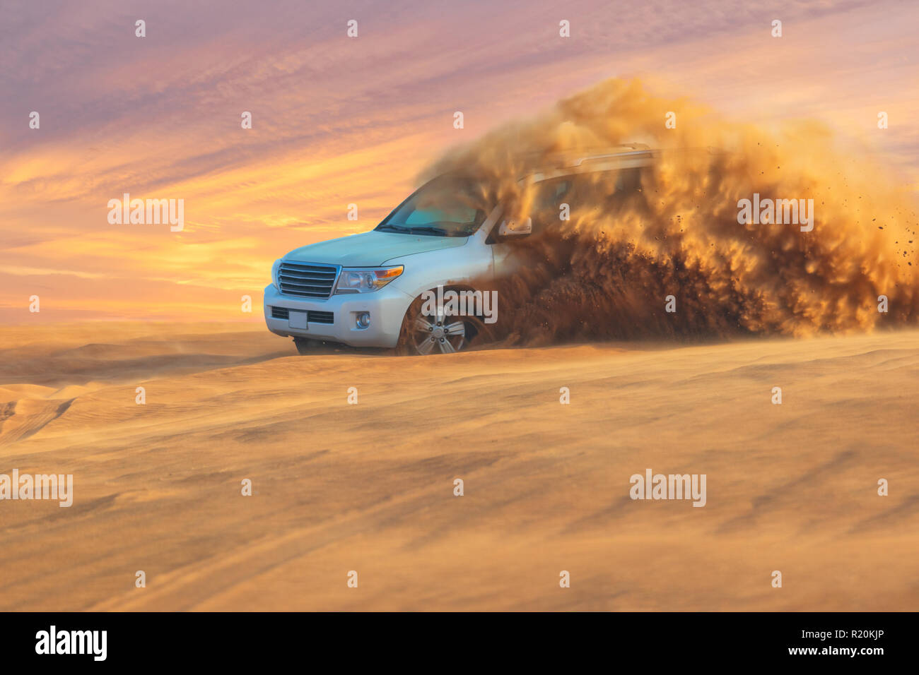 Off-road safari adventure with SUV in Arabian Desert at sunset. Offroad vehicle bashing through sand dunes in Dubai desert. Stock Photo