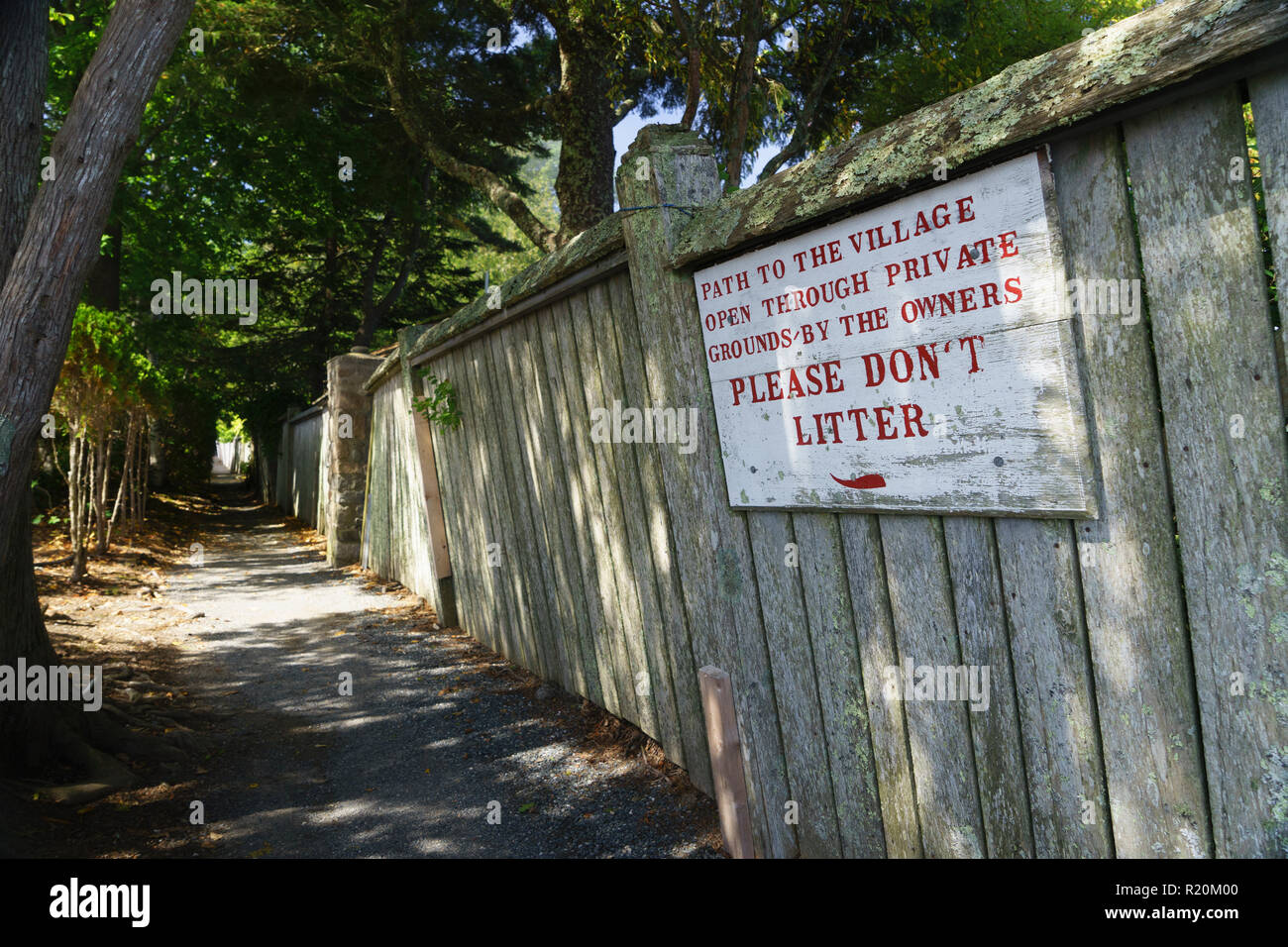 Path opened through private grounds and no littering sign on an old wooden fence, Bar Harbor, Maine, USA. Stock Photo