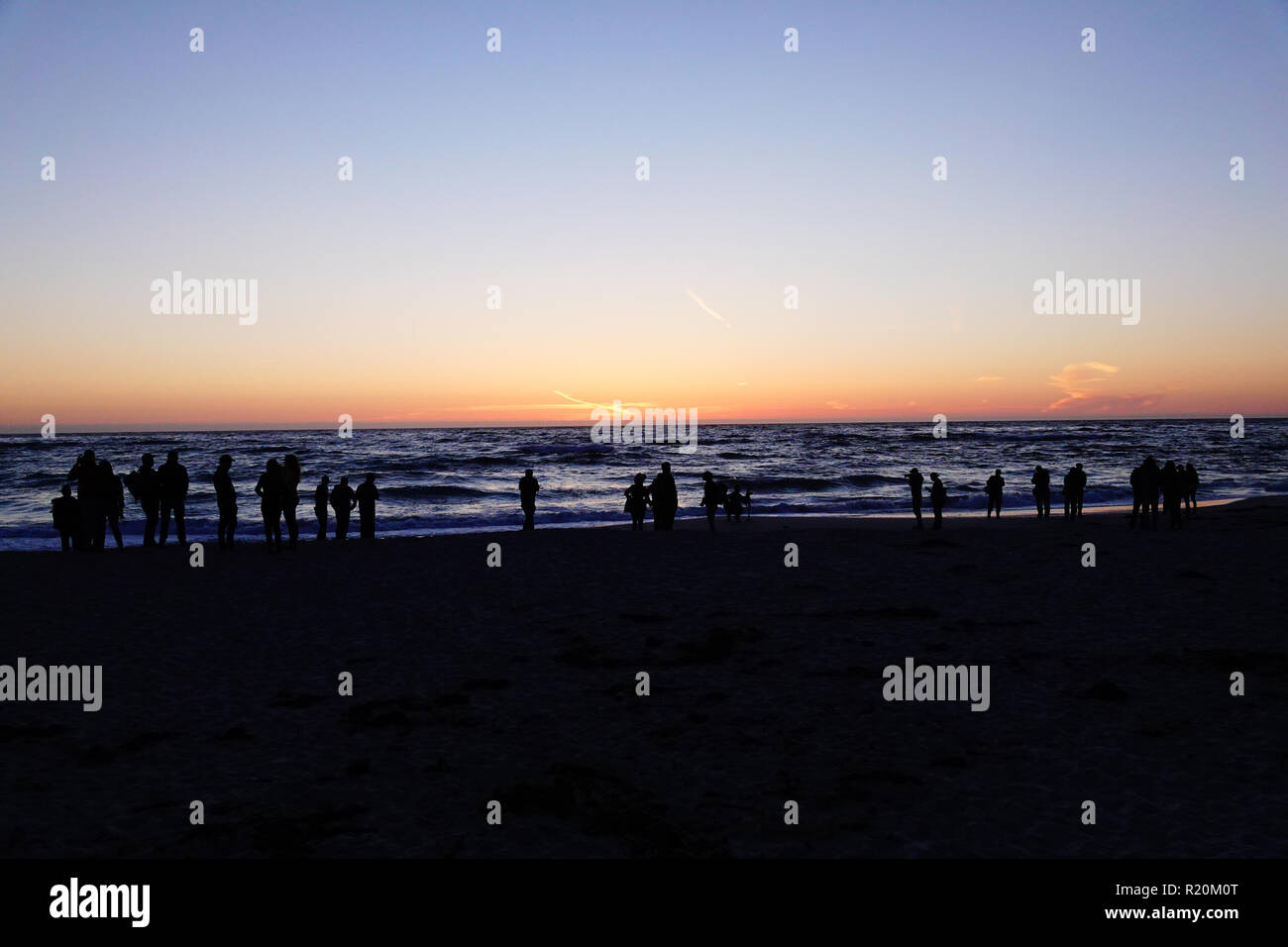 A silhouette of a surfer at sunset. Stock Photo