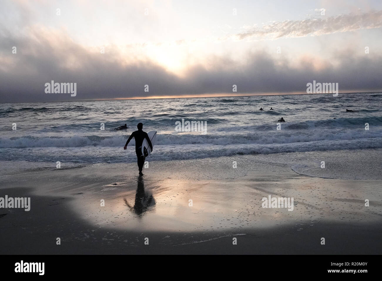 A silhouette of a surfer at sunset. Stock Photo