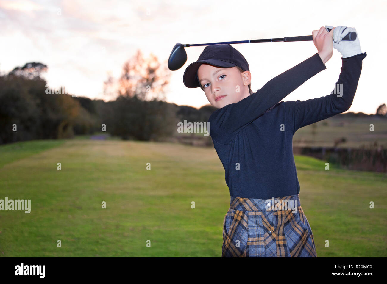 A junior female golfer at the end of her golf swing. Stock Photo