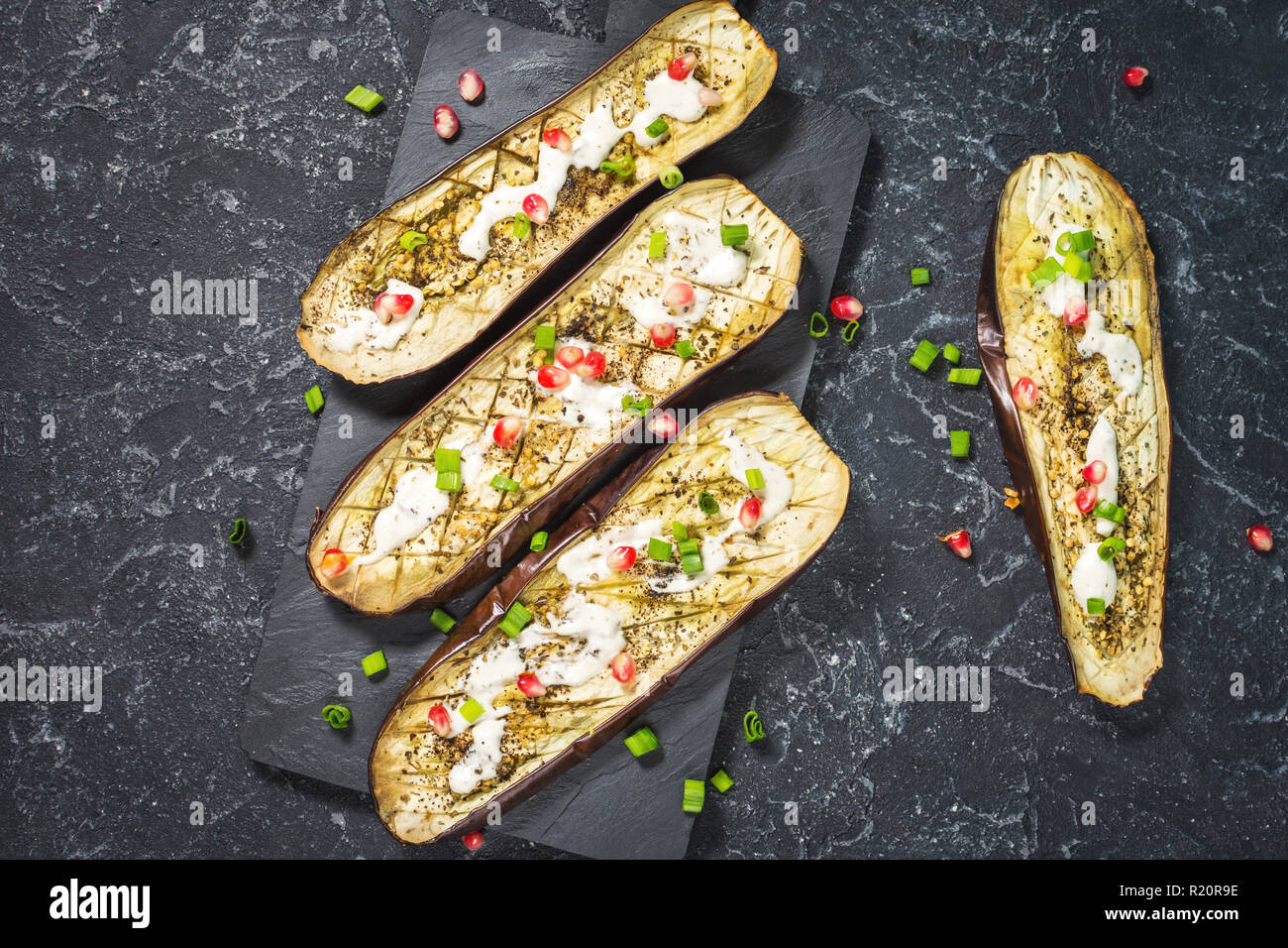 grilled eggplants with garlic yogurt sauce and pomegranate on black