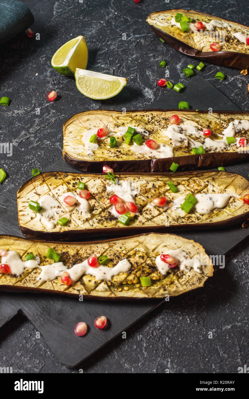 grilled eggplants with garlic yogurt sauce and pomegranate on black