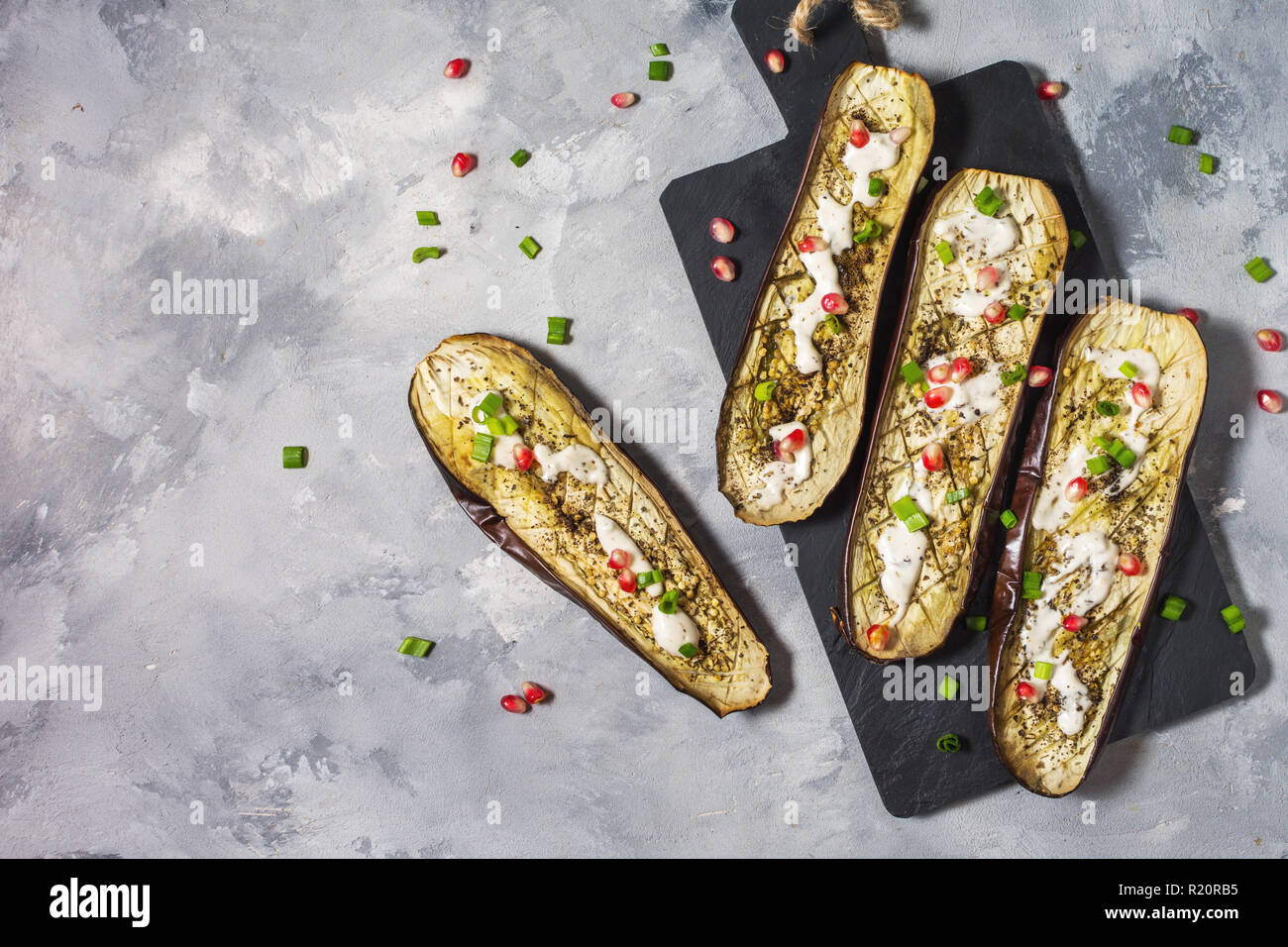 grilled eggplants with garlic yogurt sauce and pomegranate on concrete