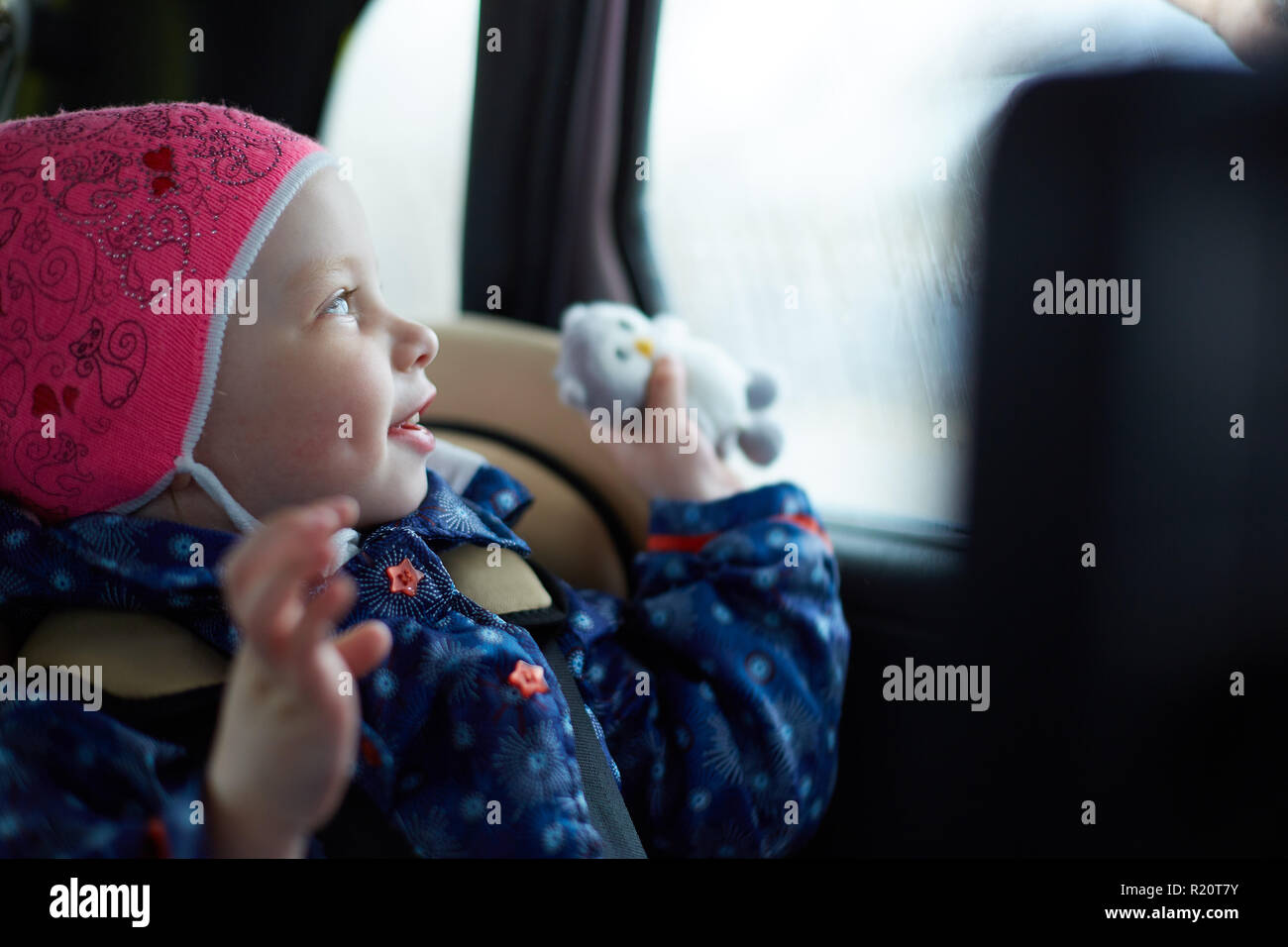 little girl with blue eyes sitting in a child seat in the back seat of ...