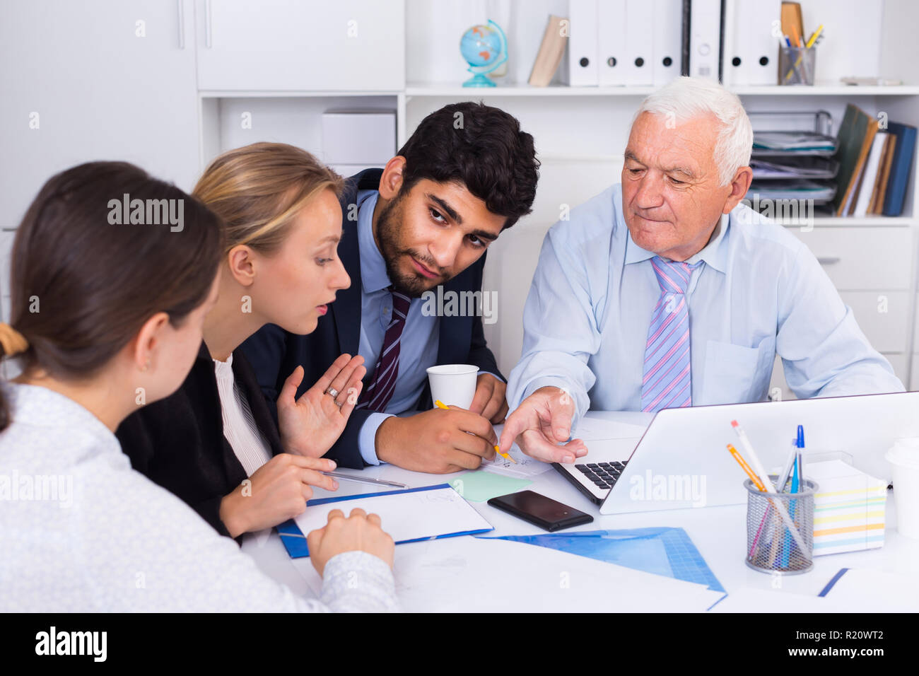 Managers are writing financial reports and discussing with mature boss in the office. Stock Photo