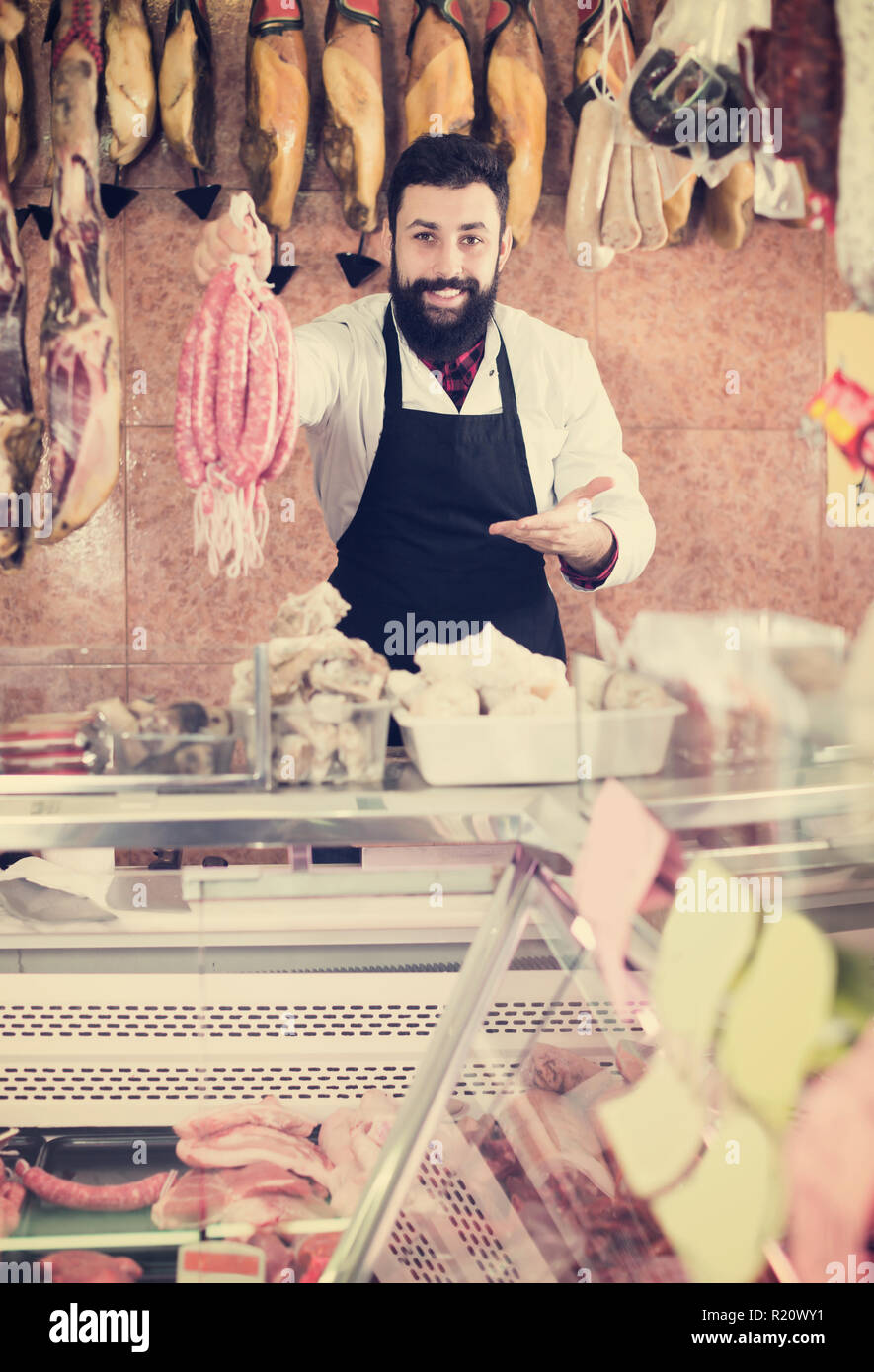 Positive man seller showing different sausages in butcher’s shop Stock Photo Alamy