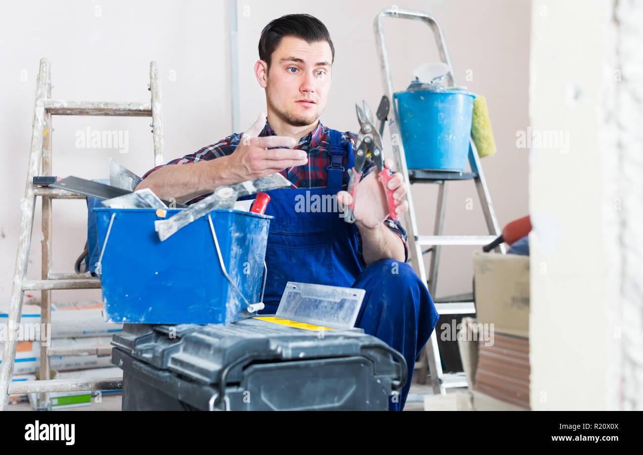 Young professional builder handyman choosing necessary tool in toolbox Stock Photo