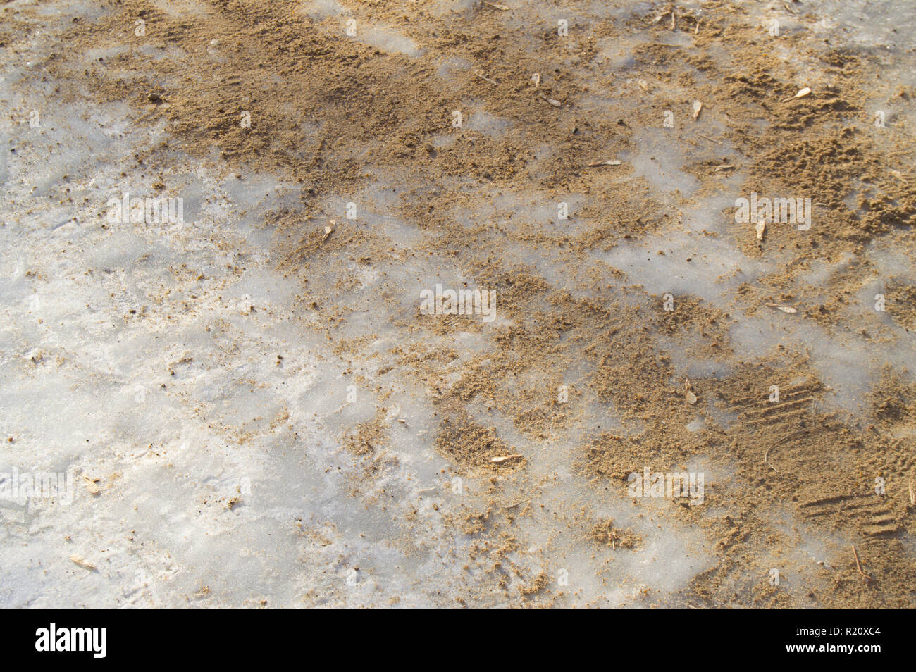 Antiicing agent and sand on the footpath covered with ice Stock Photo