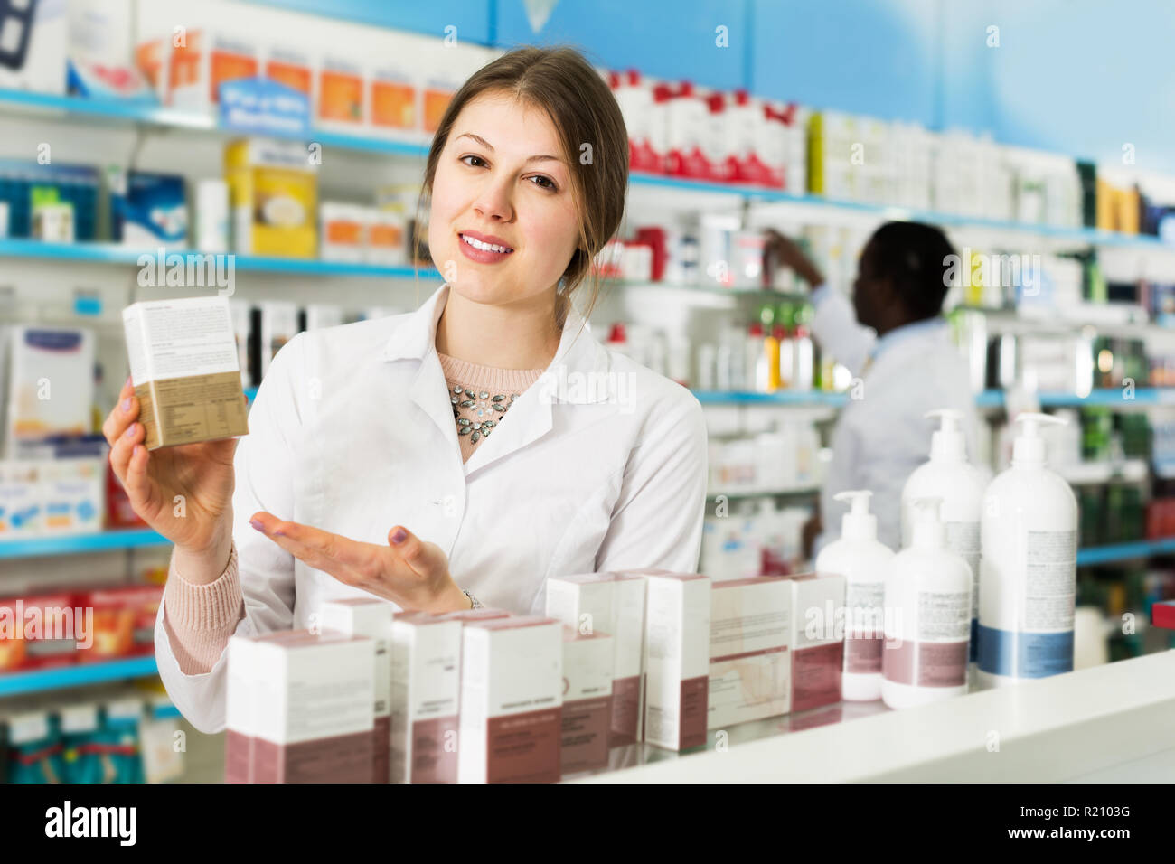 Confident woman pharmacist with medicines on background with male colleague  in pharmacy Stock Photo - Alamy