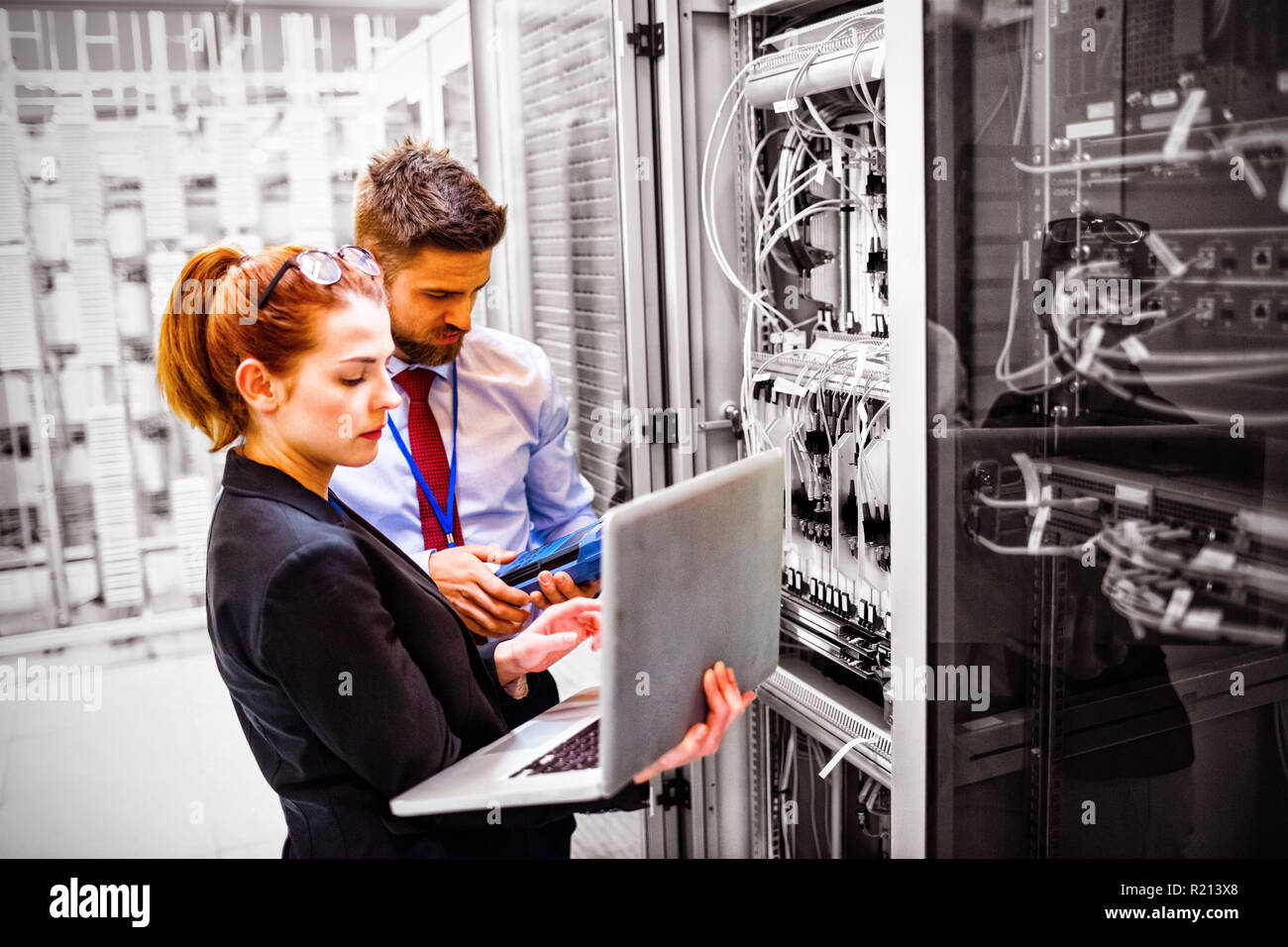 Technicians using laptop while analyzing server Stock Photo