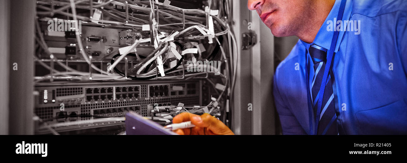 Technician maintaining record of rack mounted server on clipboard Stock Photo