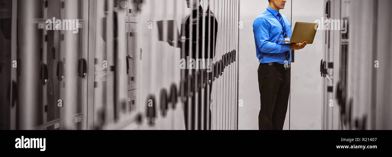 Technician using laptop while analyzing server Stock Photo
