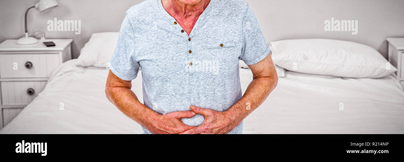 Sad senior man touching stomach at home Stock Photo
