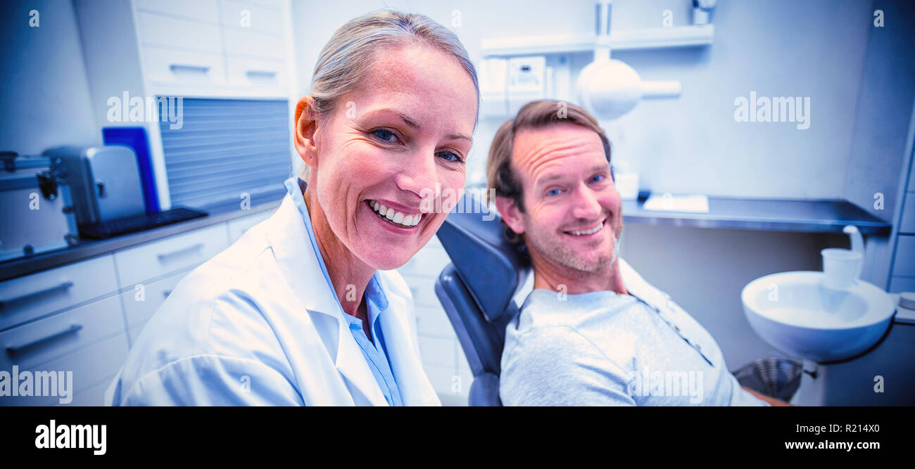 Female dentist writing on clipboard while interacting with male patient Stock Photo