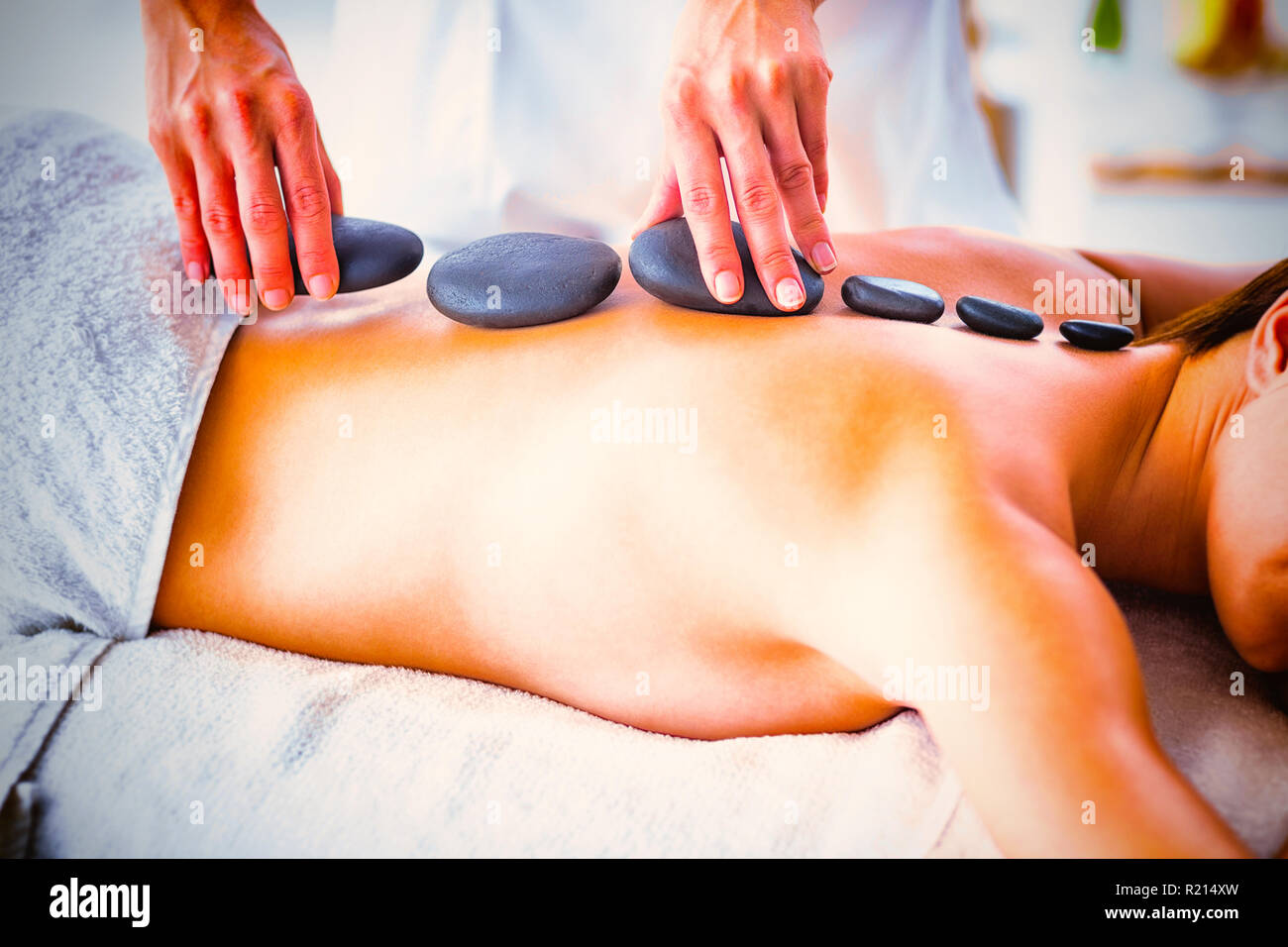 Masseur giving hot stone massage to woman Stock Photo