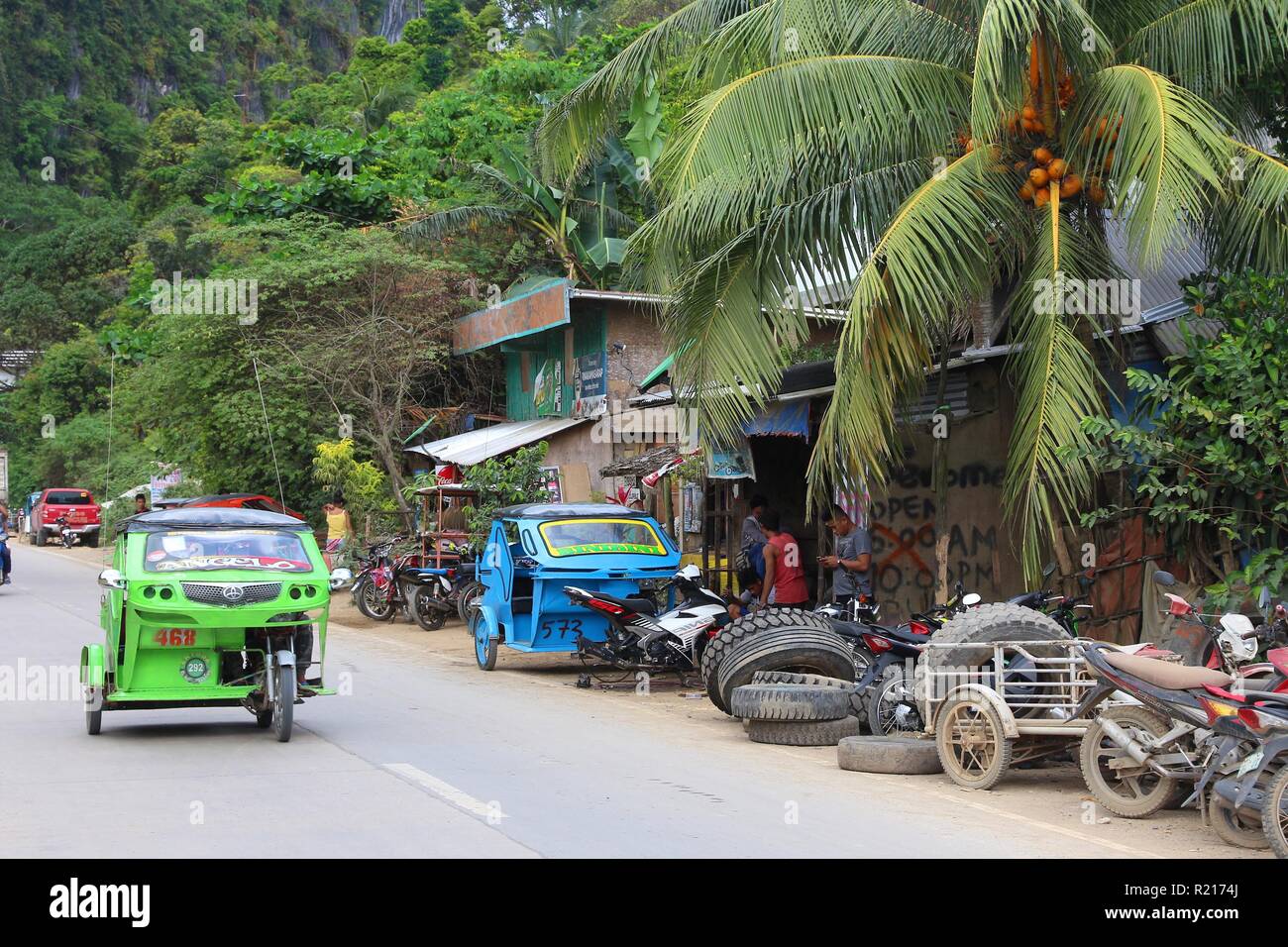 PALAWAN, PHILIPPINES - DECEMBER 4, 2017: Tourists ride tricycle taxis in resort town of El Nido in Palawan island, Philippines. 6 million foreign tour Stock Photo