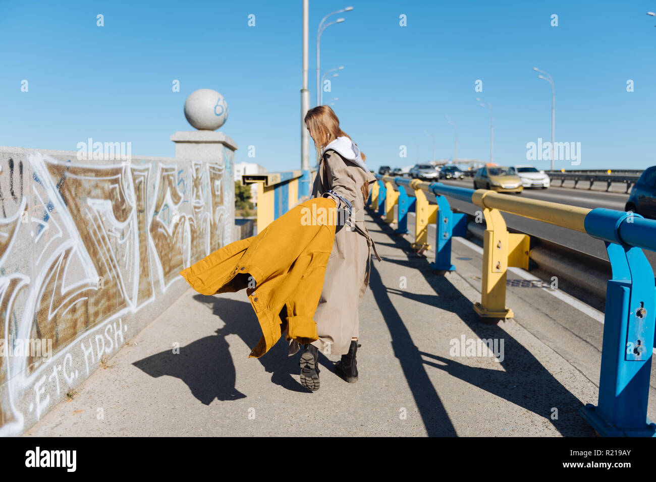 Dark-haired woman wearing long trench coat walking the bridge Stock ...