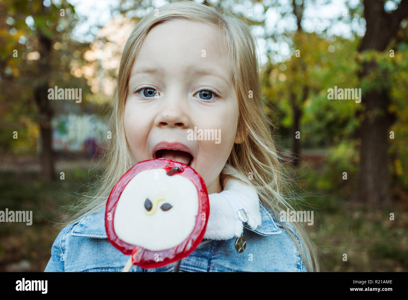 Cute little girl with big colorful lollipop. Child eating sweet candy. Stock Photo
