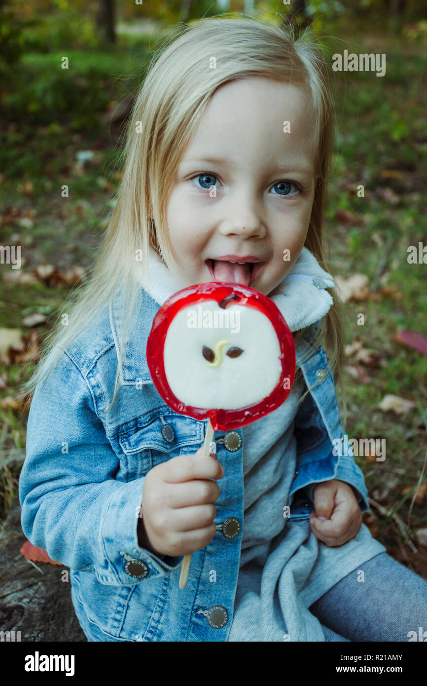 Cute little girl with big colorful lollipop. Child eating sweet candy. Stock Photo