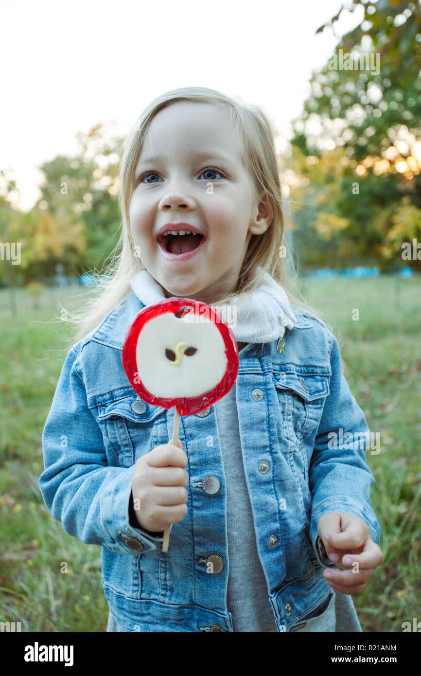 Cute little girl with big colorful lollipop. Child eating sweet candy. Stock Photo