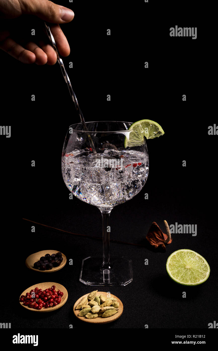 barman preparing a gin and tonic cocktail on a black background next to