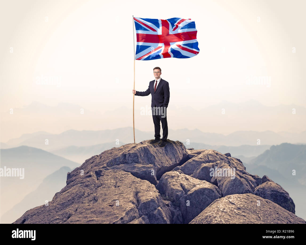 Successful businessman on the top of a mountain holding victory flag ...