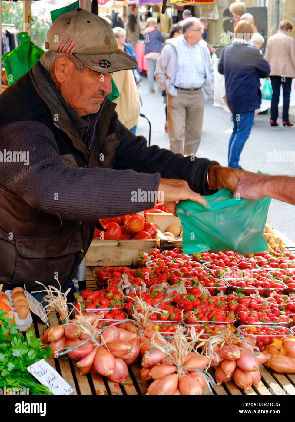 St-Cyprien, Dordogne, France - 24th September 2015: A characterful fruit stallholder hands over a purchase at the Sunday street market in St-Cyprien, Dordogne, France Stock Photo