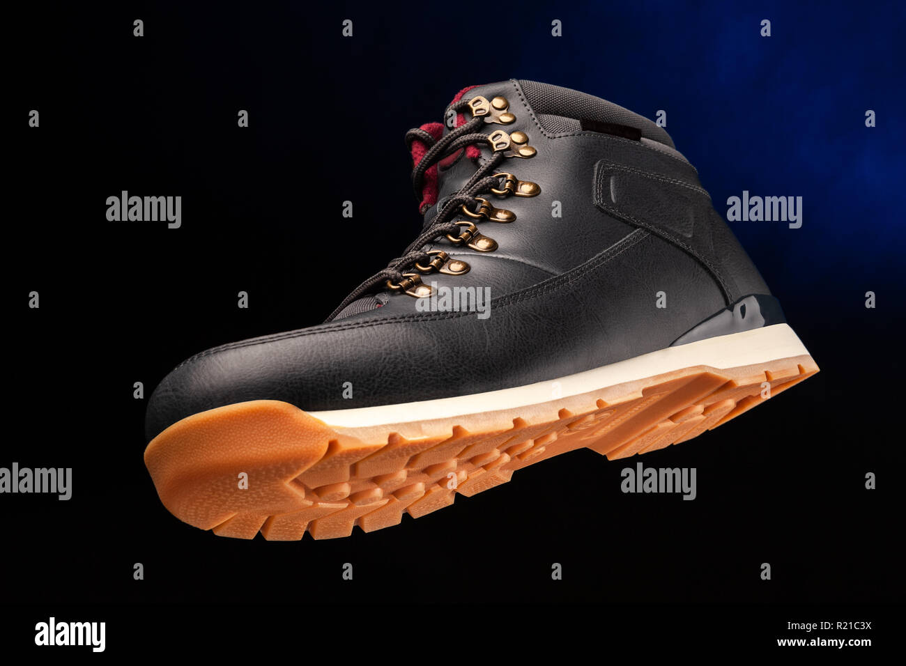 Close up view of a modern black boot on dark blue background. Stock Photo