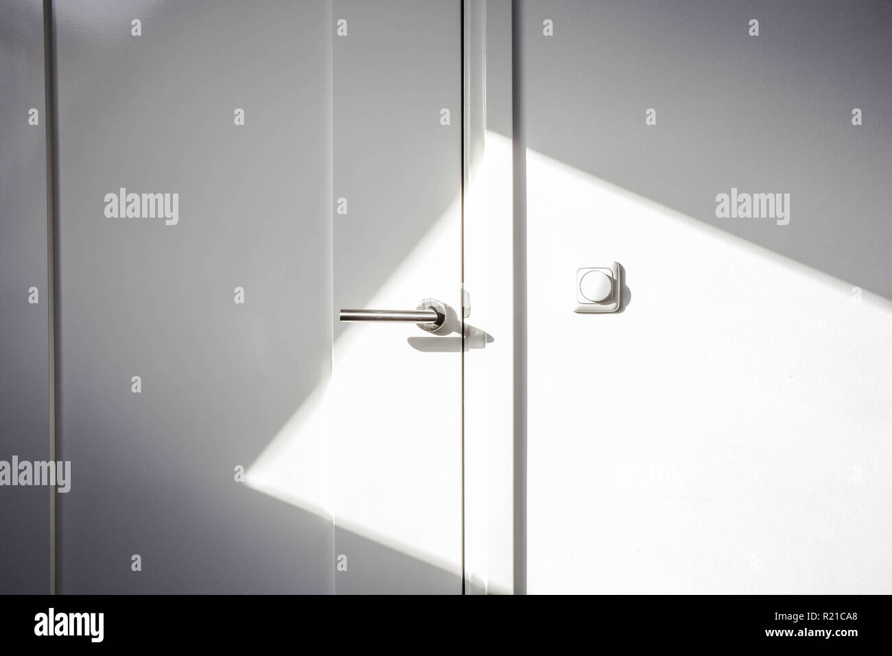 Close-up white door with sunlight. Chrome door ,The light switch on the wall modern design empty and clean Stock Photo