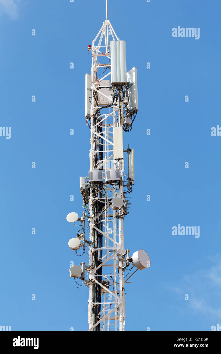 Telecommunications tower against blue sky, with mobile antennas Stock Photo