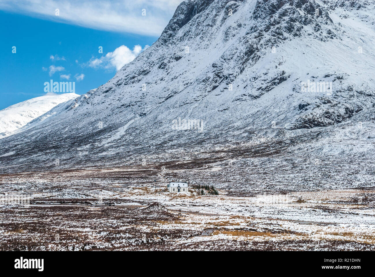 A lonely house under snowcapped mountains in the Pass of Glencoe (Glen Coe) in the Scottish Highlands Stock Photo