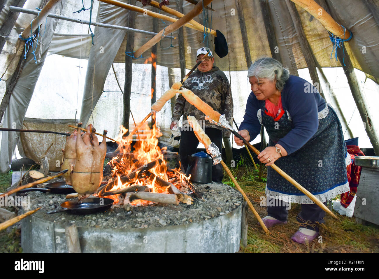 Cree people cooking wild bannock and geese in a teepee in Northern Quebec Stock Photo