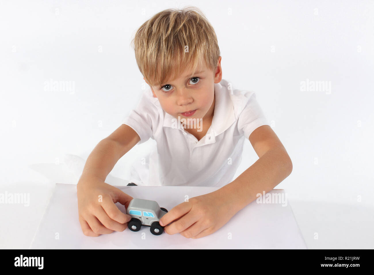 Adorable little boy playing with a small wooden car toy Stock Photo