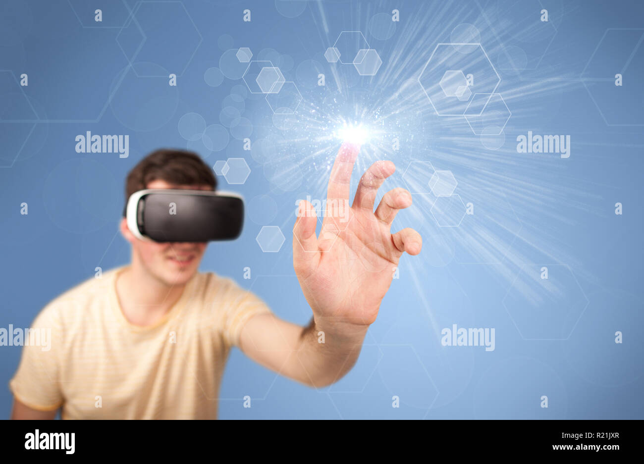 Young impressed man wearing virtual reality goggles with blue hexagons ...