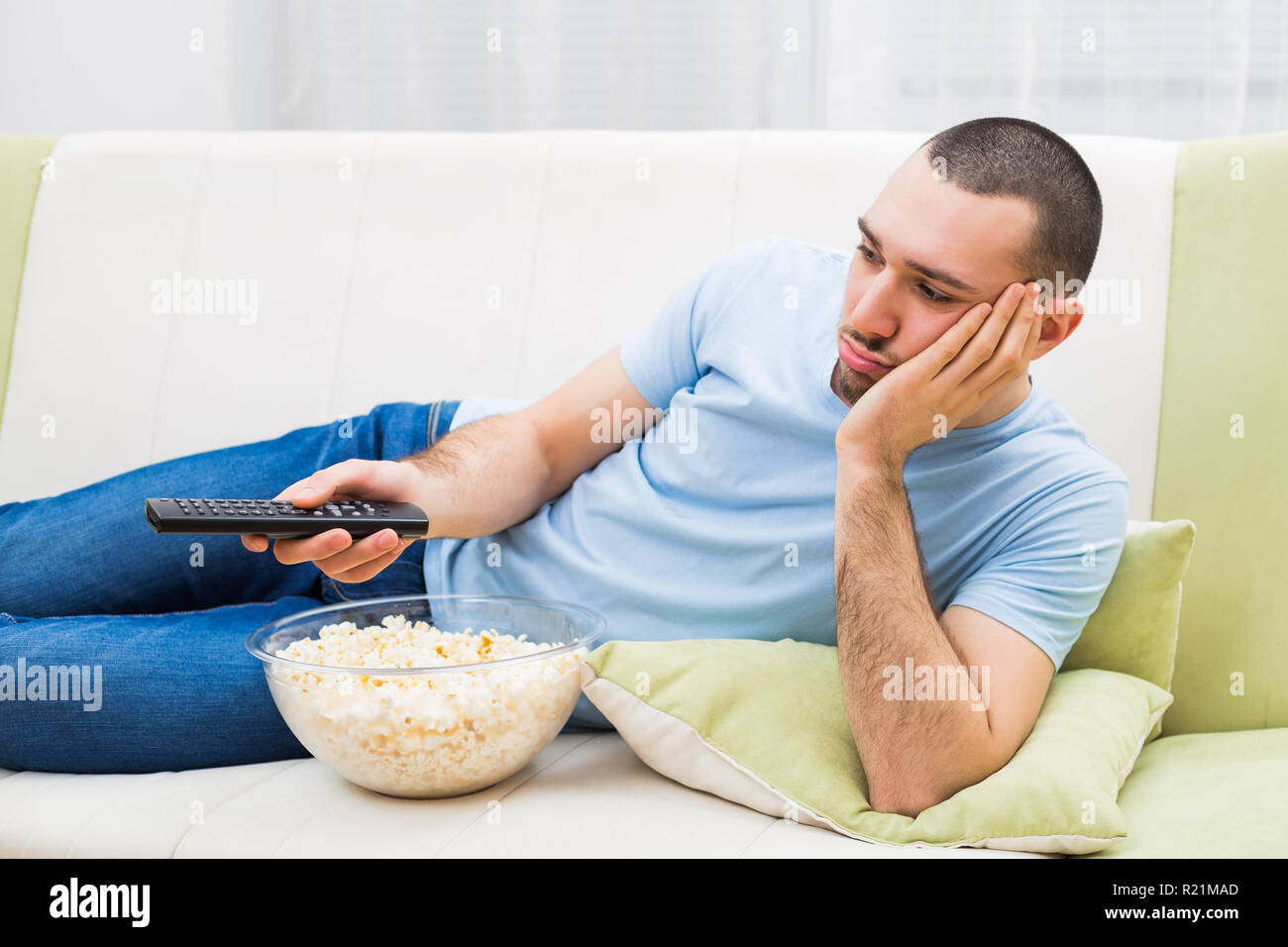 Young man is feeling boredom and changing channels on tv. Stock Photo