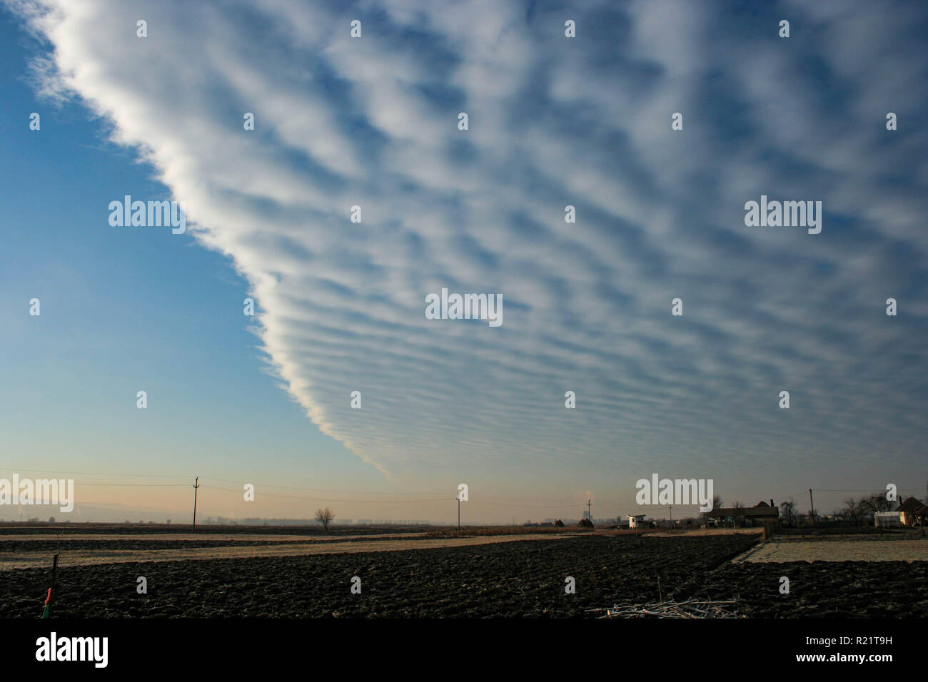 A field of altocumulus clouds with a sharp edge is invading the sky over Transylvania, Romania. Indicative of an approaching weather front. Stock Photo