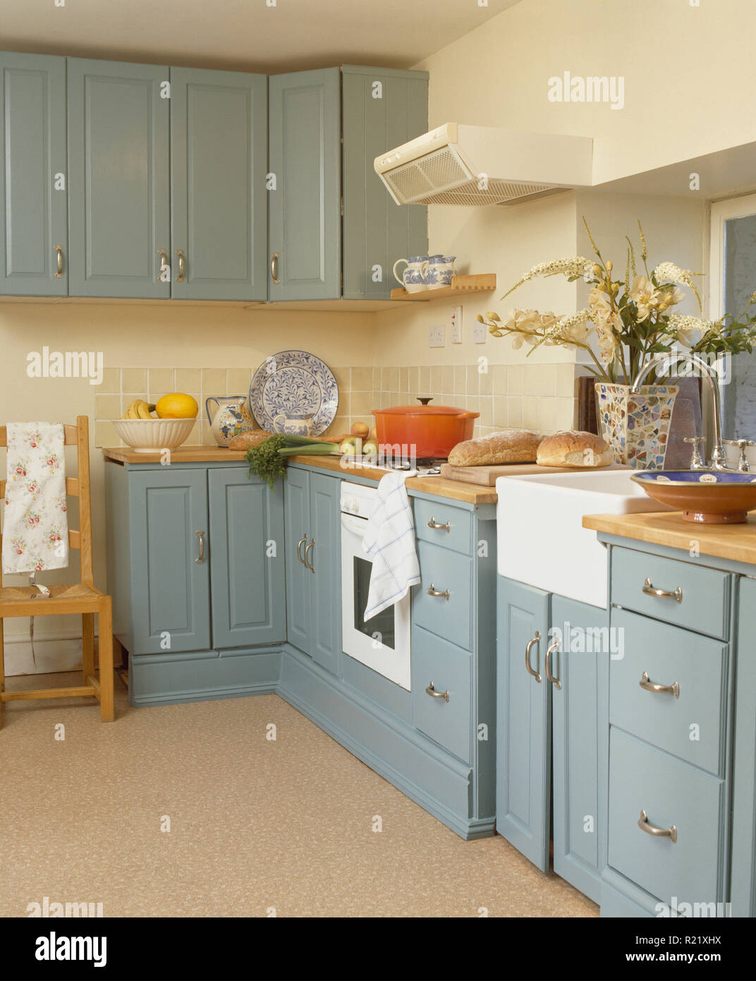 Pale blue fitted units in country kitchen Stock Photo