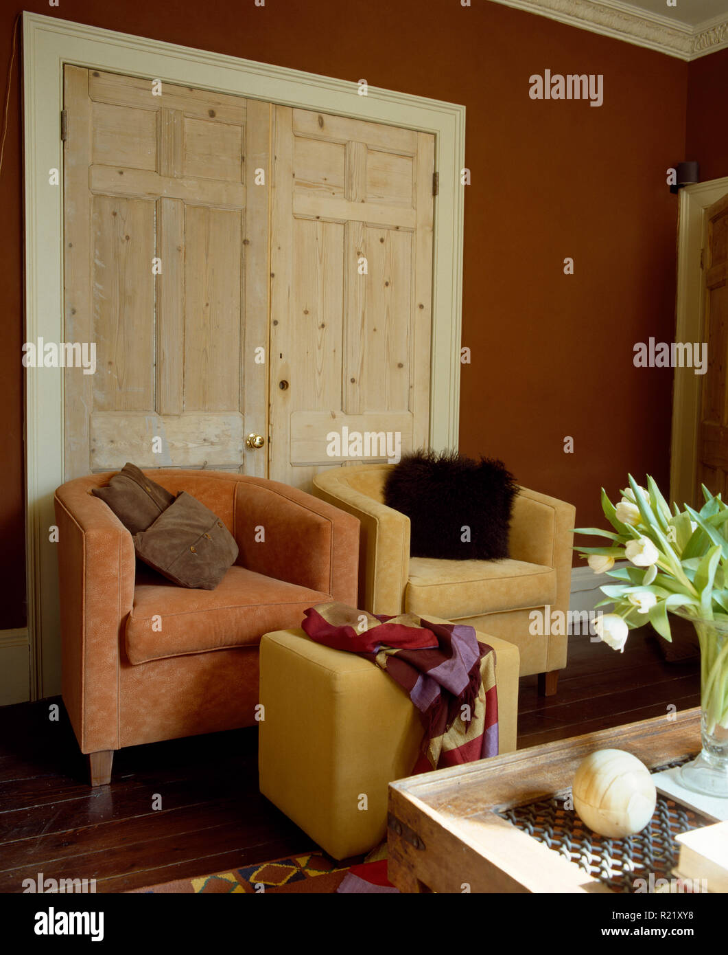 Velour armchairs in front of stripped pine double doors Stock Photo